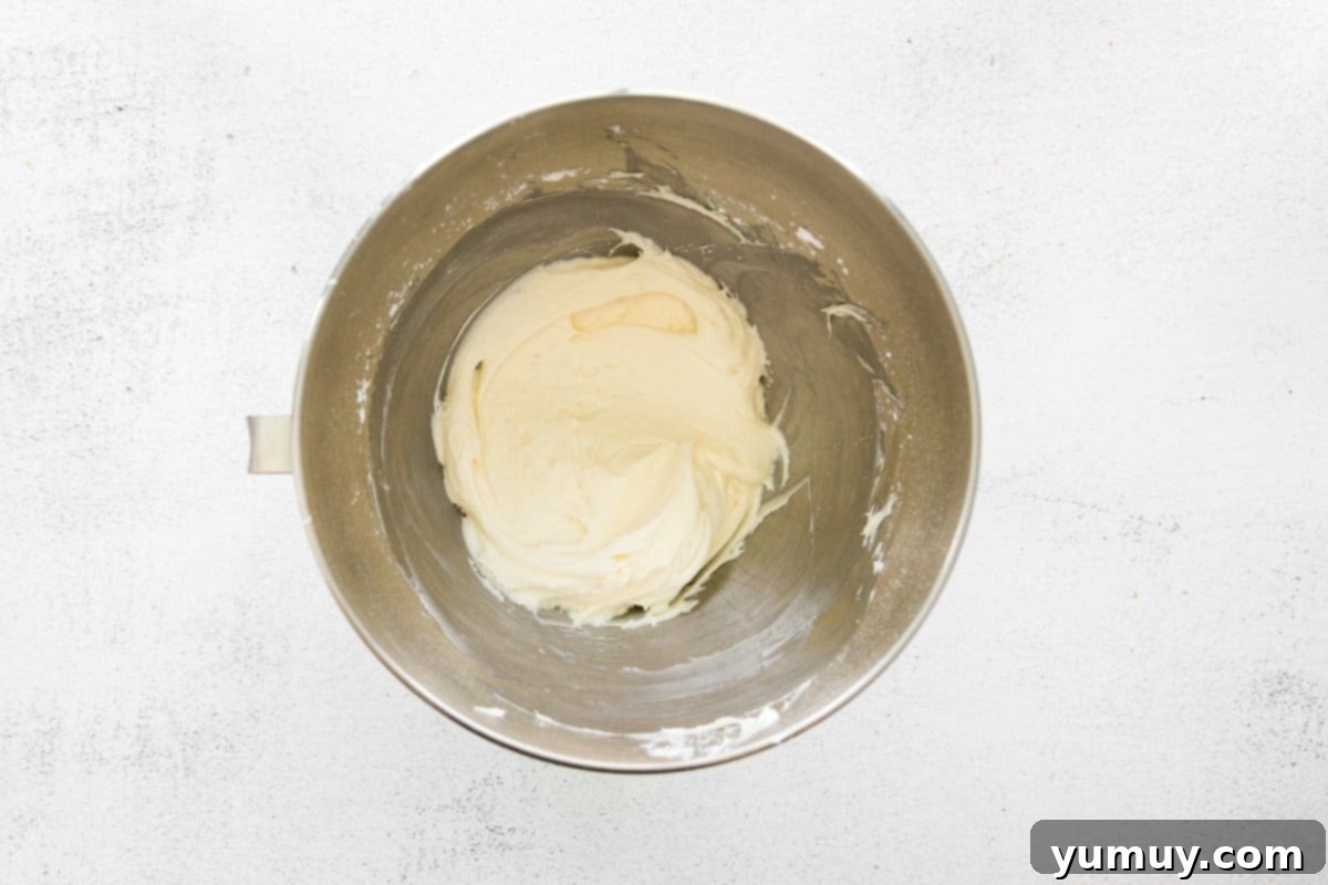 Velvety smooth cream cheese frosting, ready to adorn the chai cupcakes, in a stainless steel mixing bowl.