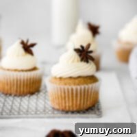 A trio of chai cupcakes, artfully frosted with cream cheese and garnished with a sprinkle of spice.