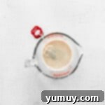 Chai tea steeping in milk in a glass bowl, infusing its rich flavor.