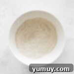 Dry ingredients for chai cupcakes, including cake mix and chai spice, in a white bowl.