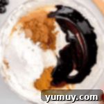 Luscious Chocolate Fruit Delight 6 Chocolate syrup, sugar, and spices are being added to the whipped topping mixture in a glass bowl, creating a rich blend.