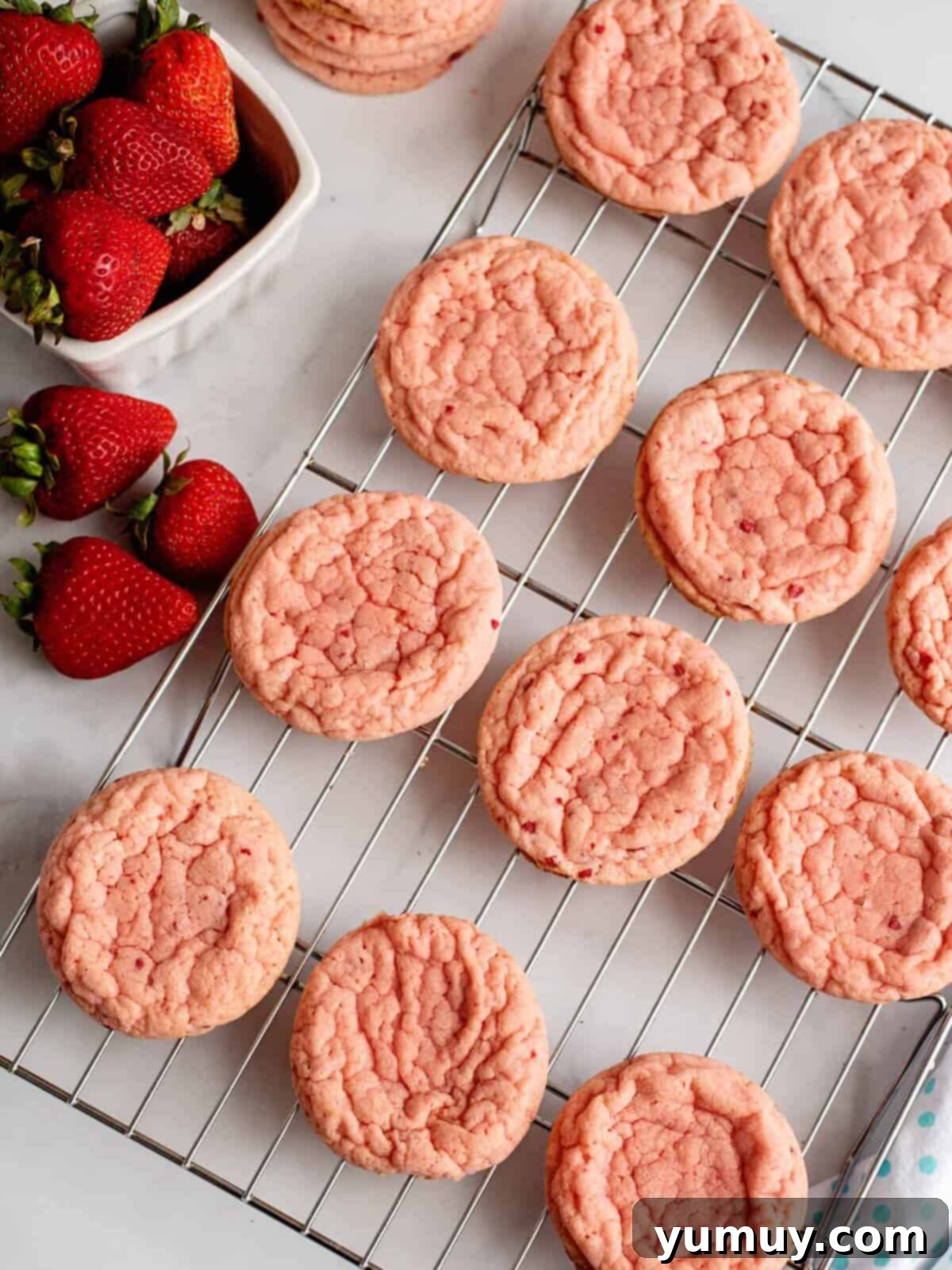 The Baker's 9 Essential Cookie Foundations 15 baked strawberry cookies on a wire rack.
