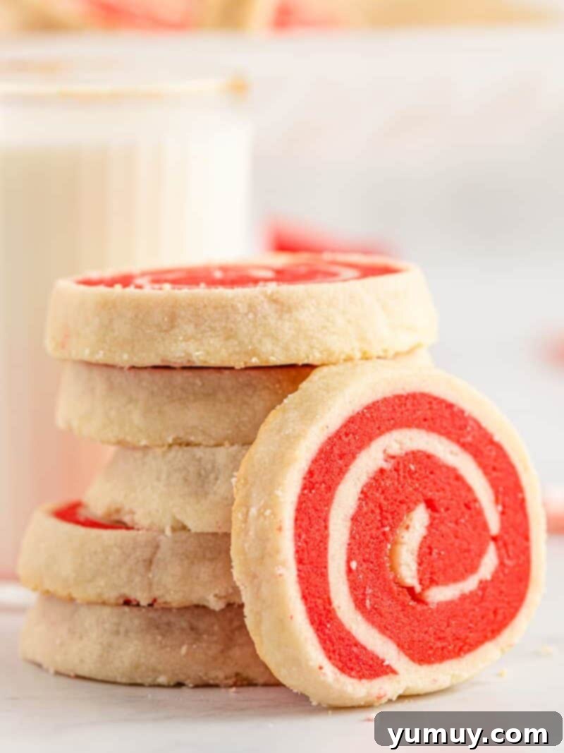 The Baker's 9 Essential Cookie Foundations 8 stack of white and red pinwheel cookies with one leaned up showing the swirl