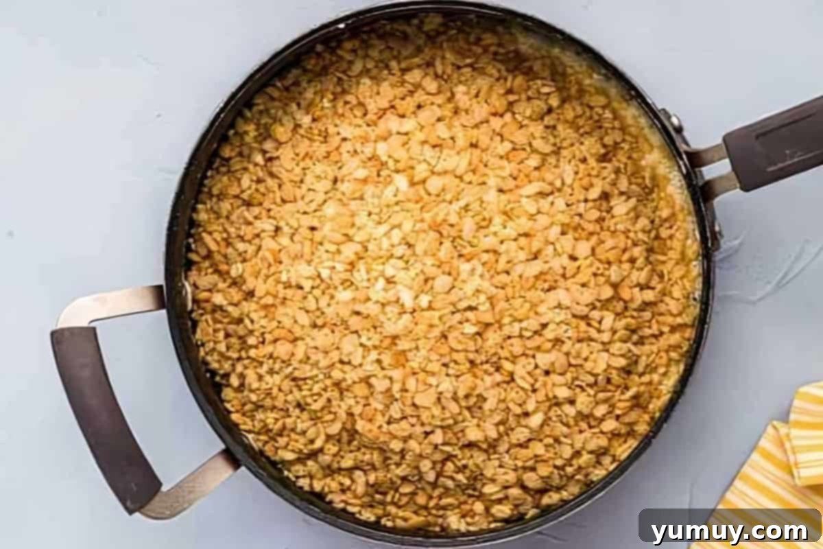 Chocolate Crackle Squares 8 Rice Krispies cereal being stirred into melted marshmallow mixture.