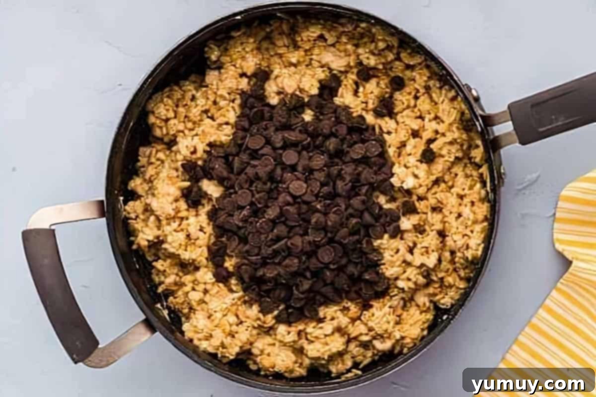 Chocolate Crackle Squares 9 Chocolate chips being mixed into the Rice Krispies and marshmallow mixture, turning it chocolatey.
