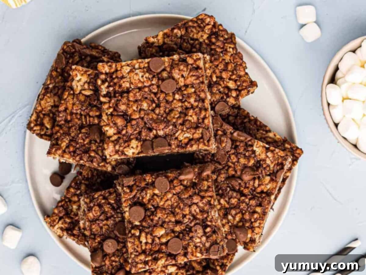 Chocolate Crackle Squares 11 Chocolate rice krispie treats with chocolate chips, stacked on a plate, ready to be served.