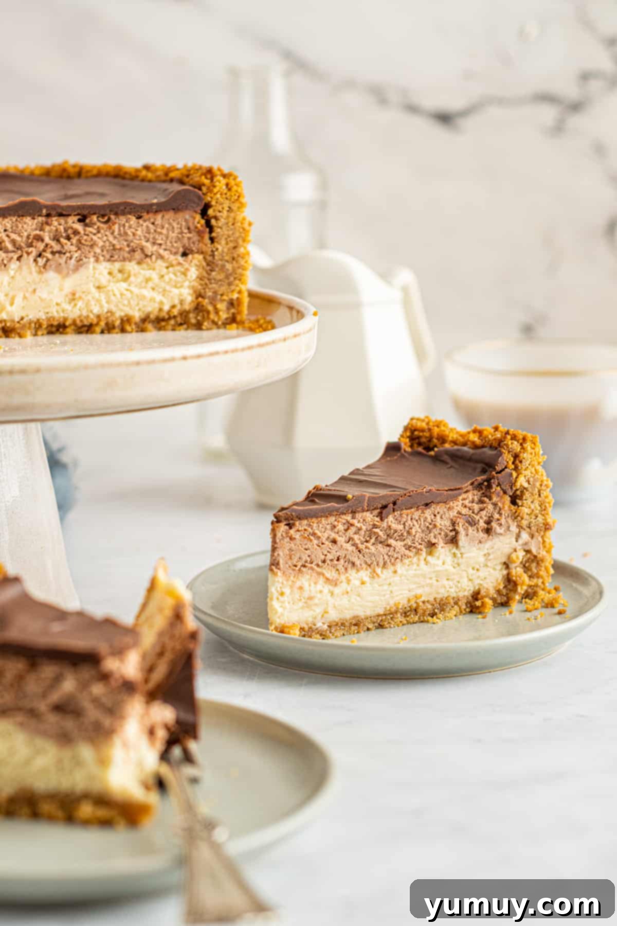Slices of chocolate caramel cheesecake on white plates, showcasing the distinct layers.