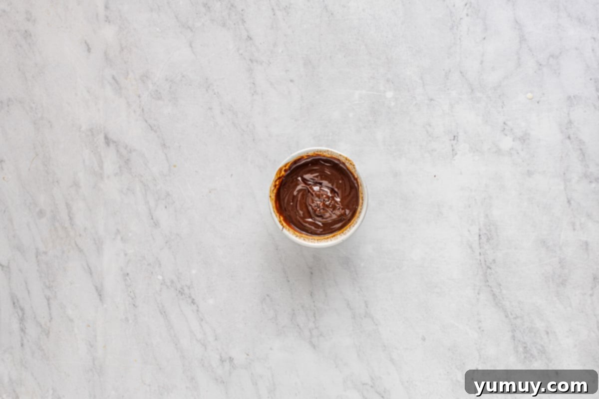 Smooth chocolate ganache in a small white bowl.