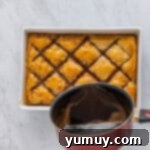 Sweet & Crispy Homemade Greek Baklava 11 Hot syrup being poured over freshly baked, golden-brown baklava in a baking pan.