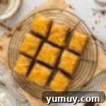 Sweet & Crispy Homemade Greek Baklava 12 Freshly cut squares of homemade baklava resting on a circular wire rack.