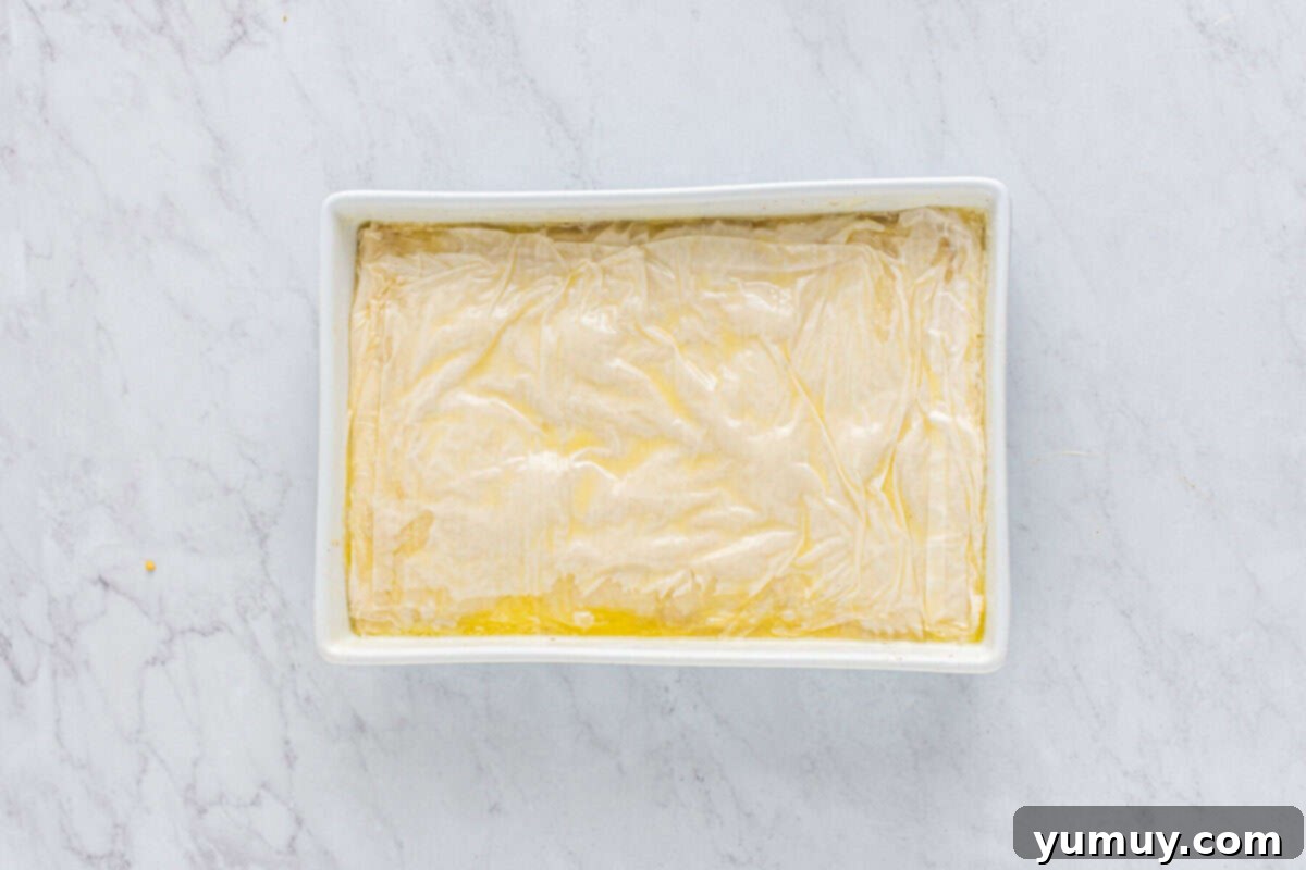 Sweet & Crispy Homemade Greek Baklava 16 The unbaked baklava in its baking pan, with all layers meticulously assembled and buttered.