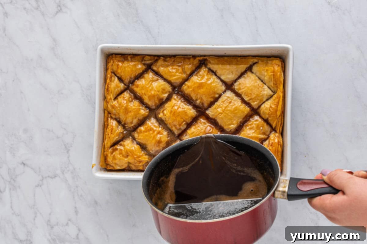 Sweet & Crispy Homemade Greek Baklava 19 The delicious hot syrup being poured over the freshly baked homemade baklava in a baking pan.