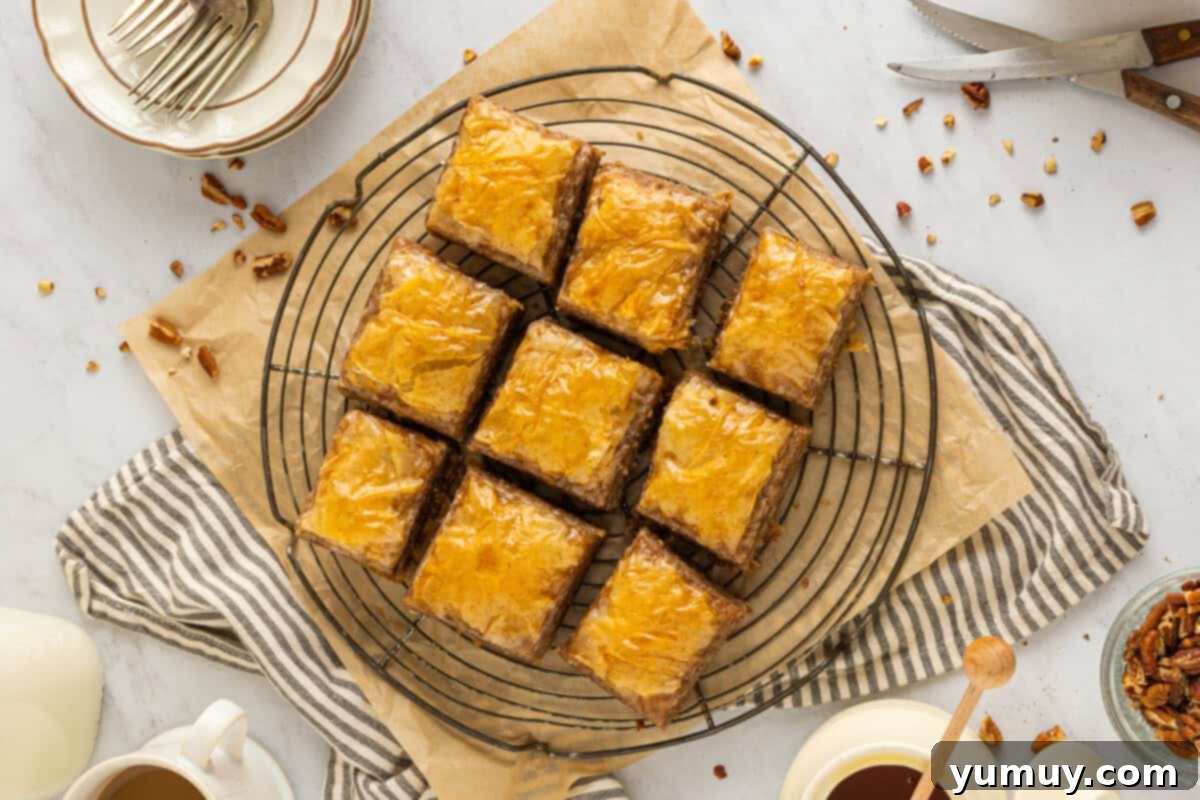 Sweet & Crispy Homemade Greek Baklava 20 Nine perfectly cut squares of homemade baklava resting on a circular wire rack, glistening with honey.