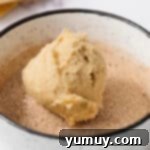 dipping a churro cookie dough ball in cinnamon sugar.