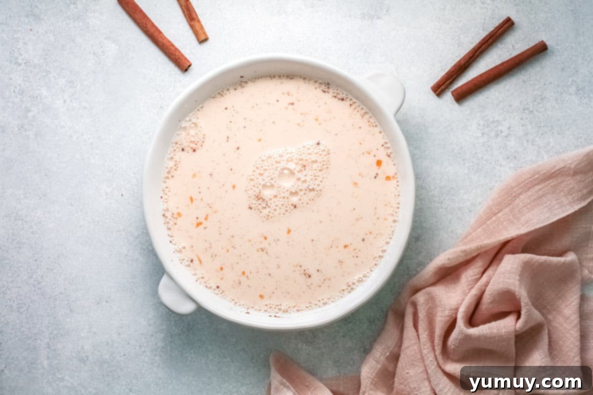 french toast egg mixture in a white bowl, whisked and ready for bread.