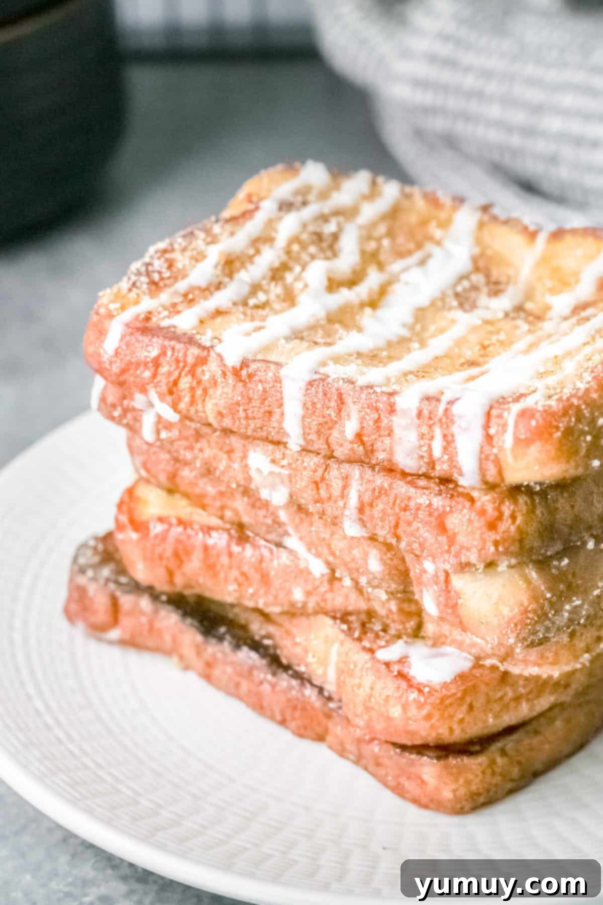 Close-up of six stacked slices of golden brown churro French toast, showing the generous cinnamon sugar coating.