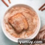 french toast slice dipped in cinnamon sugar mixture in a white bowl.