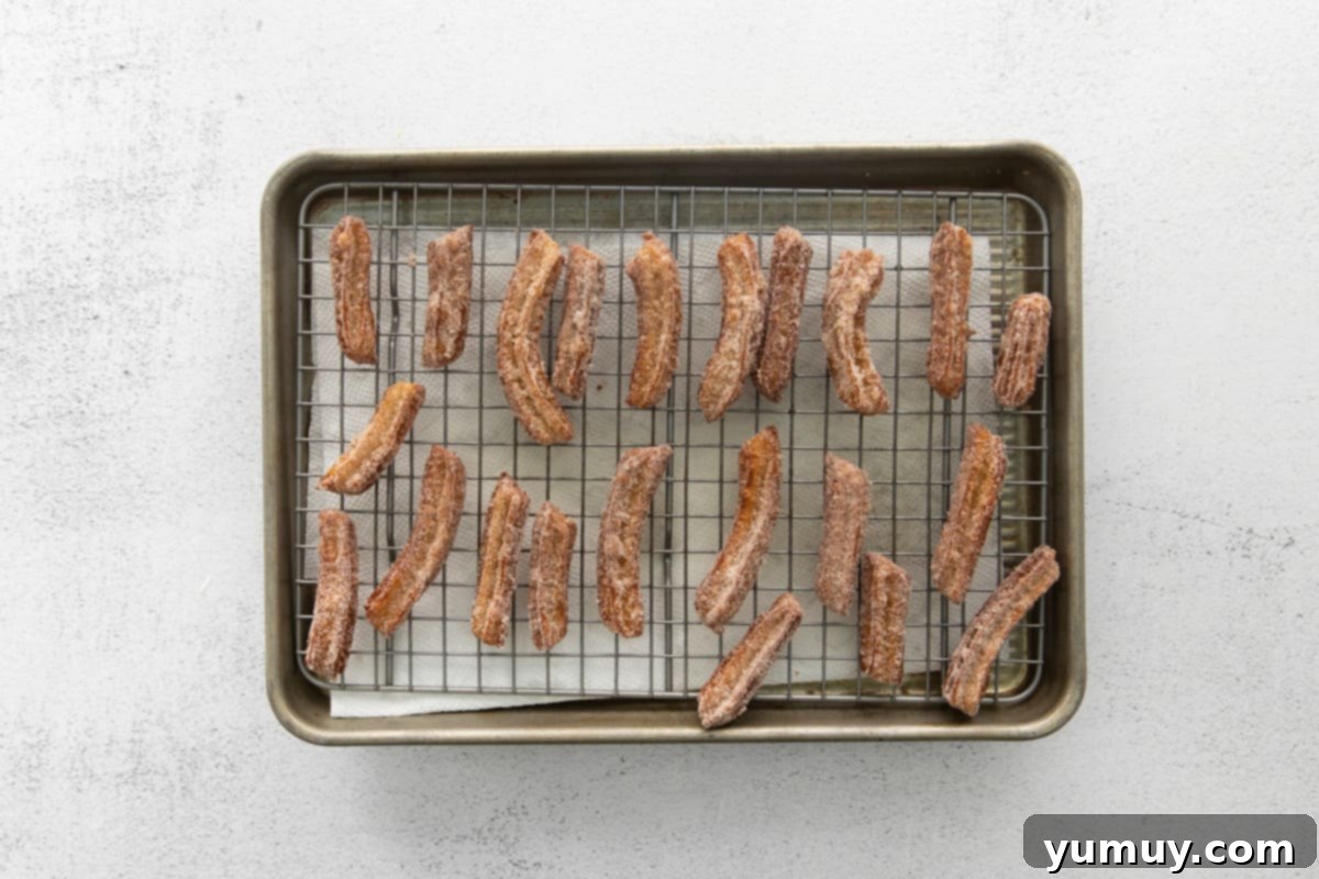 churros on a wire rack set in a baking sheet.