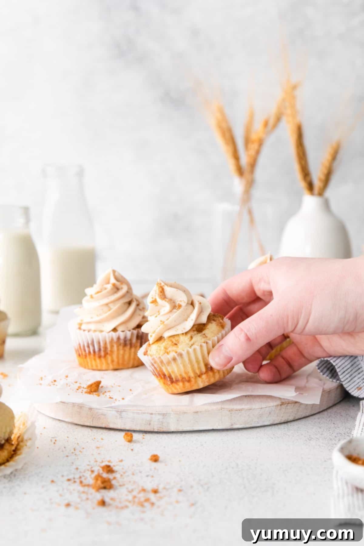 hand grabbing a cinnamon swirl cupcake from a marble serving platter.