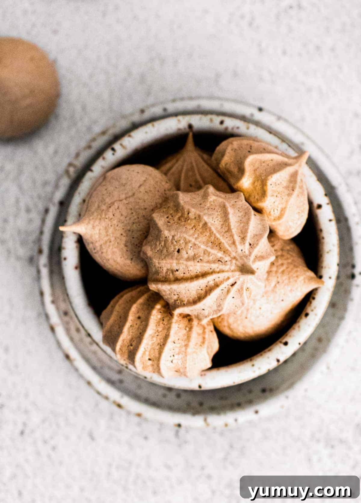 A bowl overflowing with fluffy chocolate meringue cookies, ready to be enjoyed.