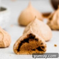 A chocolate meringue cookie sliced in half, showcasing its crispy shell and chewy chocolatey interior.