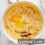 Southern Banana Pudding Cookies 7 Cookie dough in a bowl with an egg and vanilla extract being added