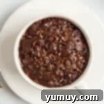 Microwaved chocolate mug cake in a white coffee cup.