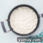 A gooey mixture of melted marshmallows and butter in a saucepan, swirling together.