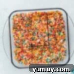 A batch of freshly made Fruity Pebbles treats cooling in a glass baking pan.