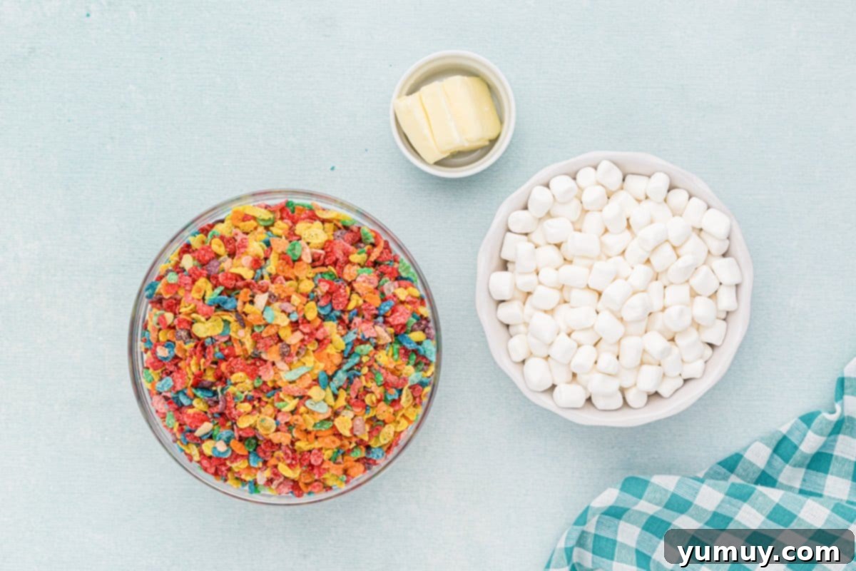 Overhead view of all the ingredients laid out for making Fruity Pebbles treats: butter, marshmallows, and Fruity Pebbles cereal.