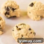 balls of edible chocolate chip cookie dough on a cutting board.
