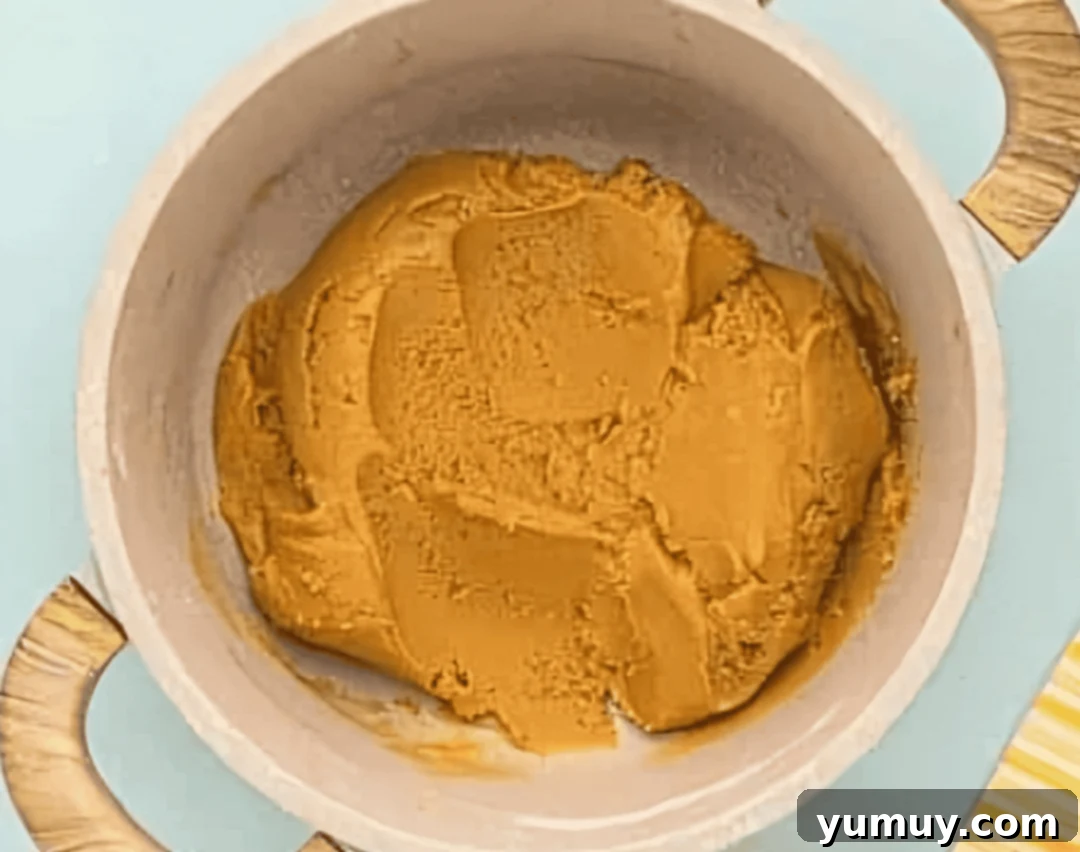 Thick, cooked peanut butter filling mixed with powdered sugar and vanilla, ready for shaping in a saucepan.