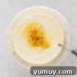 a kitchen torch caramelizing sugar on top of a cheesecake on a white cake stand.