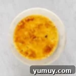 overhead view of creme brulee cheesecake on a white cake stand.