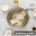 overhead view of cream cheese and sugar in a stainless mixing bowl.