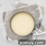 overhead view of creme brulee cheesecake batter in a springform pan on top of sheets of aluminum foil.