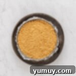 Overhead view of double crust cheesecake in a springform pan wrapped in aluminum foil and set in a larger cake pan, ready for the water bath.