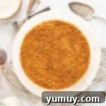 Overhead view of a beautiful double crust cheesecake on a white cake stand, ready to be served.