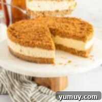 Profile view of a sliced double crust cheesecake on a white cake stand with a wooden base.