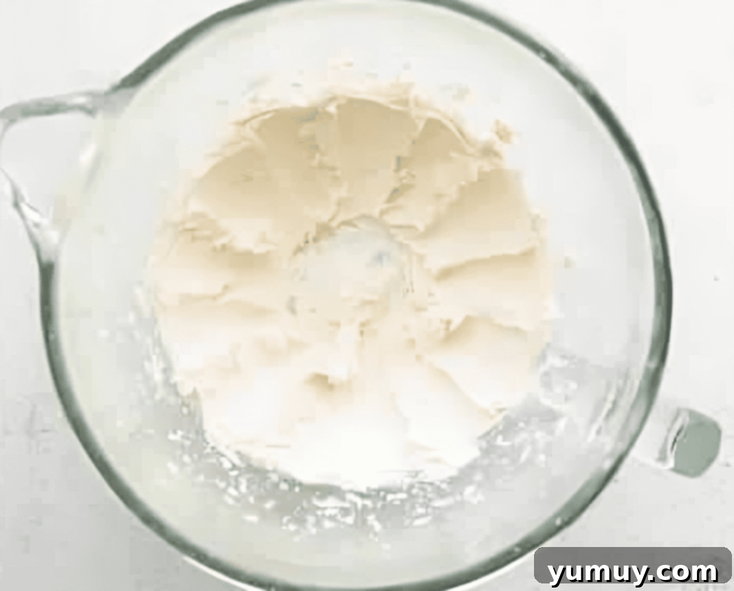 Springtime Macaron Delights 13 Vanilla buttercream being mixed in a stand mixer, showcasing its light and fluffy texture, ready for filling macarons.