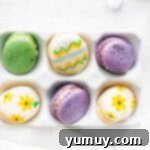 Springtime Macaron Delights 10 Overhead shot of beautifully decorated Easter egg macarons resting in an egg crate, showcasing various patterns and colors.
