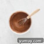 overhead view of german chocolate cake batter in a white bowl with a whisk.