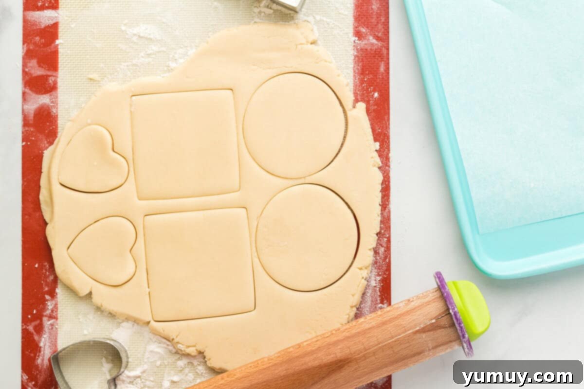 Whimsical Easter Egg Cookies 14 Overhead view of rolled out sugar cookie dough on a floured surface, with egg shapes freshly cut.
