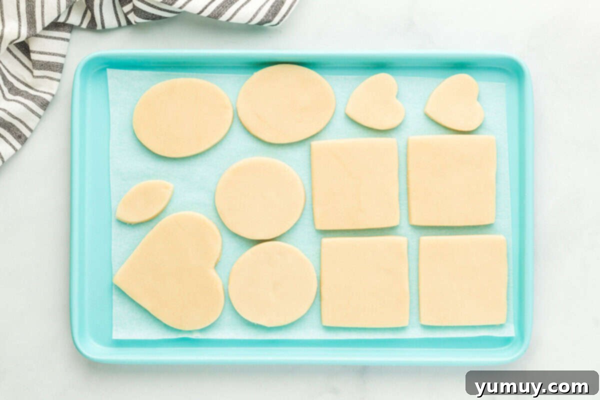 Whimsical Easter Egg Cookies 15 Overhead view of freshly cut-out Easter egg sugar cookies arranged on a blue baking sheet, ready for chilling and baking.