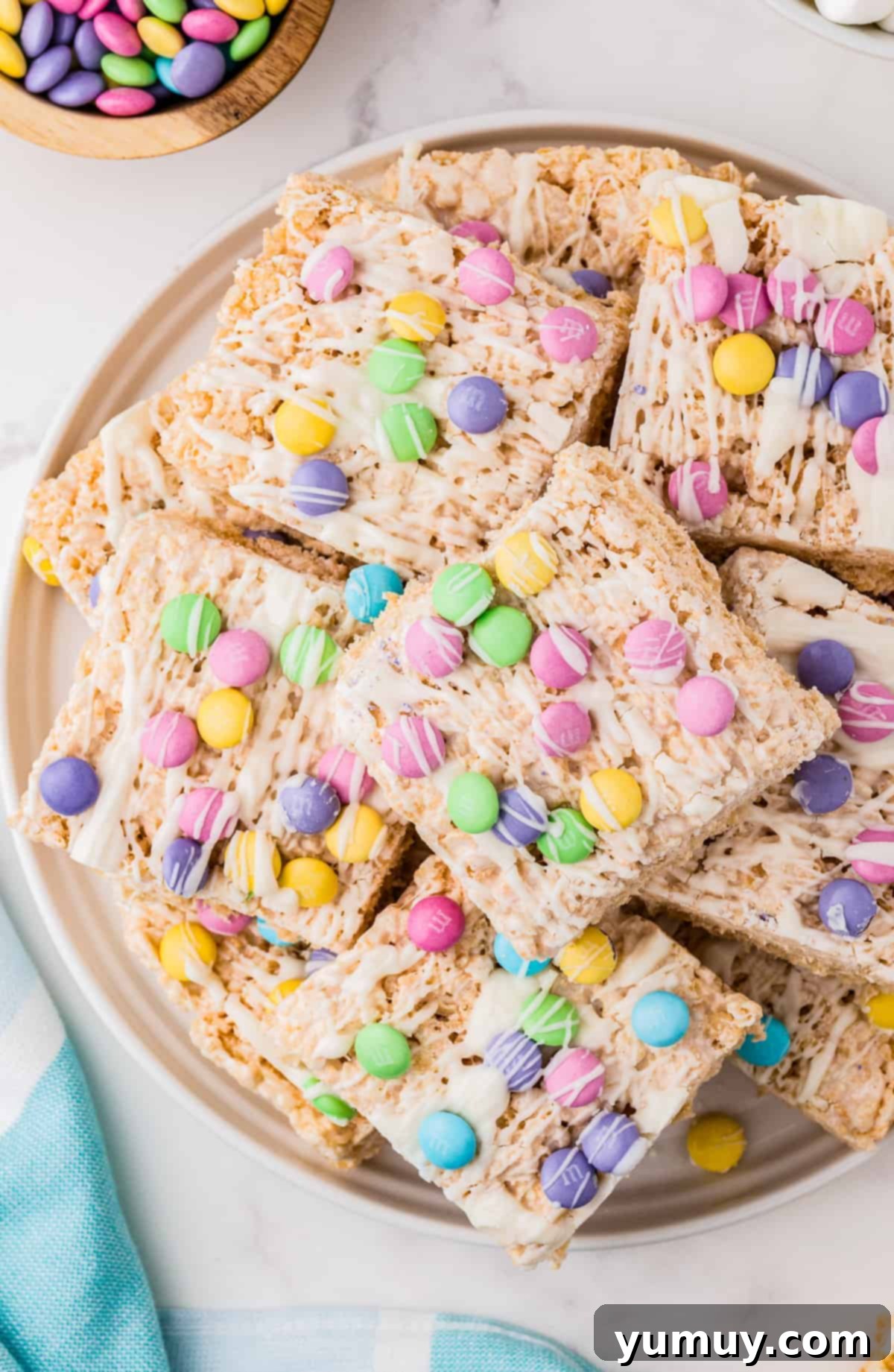 Spring Crispy Delights 2 Stacked Easter Rice Krispie Treats on a serving platter, close up, showing M&Ms and white chocolate drizzle.