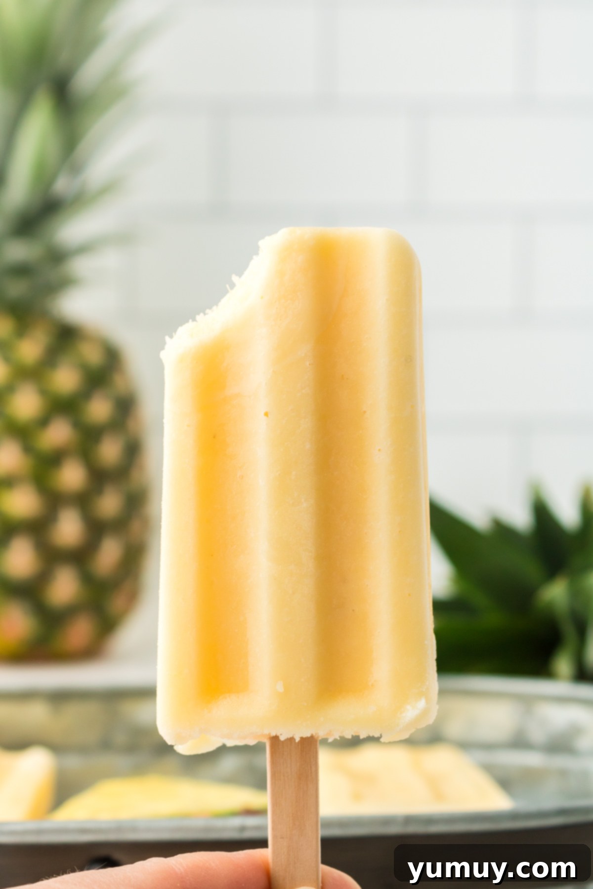Delicious Dole Whip popsicle with a bite taken out, showing its creamy pineapple texture.