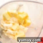 Pineapple chunks and vanilla ice cream blending together in a high-powered blender for Dole Whip popsicles.