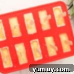 Pineapple popsicles in a mold with sticks inserted, freezing to perfection.