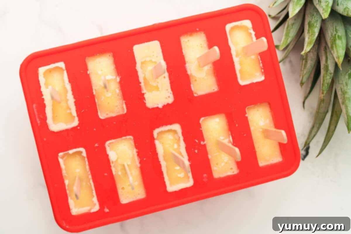 Dole Whip popsicles in a mold with sticks, undergoing the final freezing process.