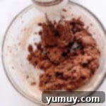 Gooey Chocolate Marshmallow Cookies 8 Mixing chocolate cookie dough with a hand mixer, ensuring all ingredients are well combined.